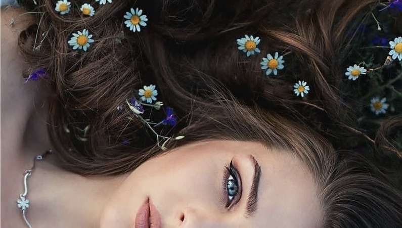 woman's face laying down with flowers in hair